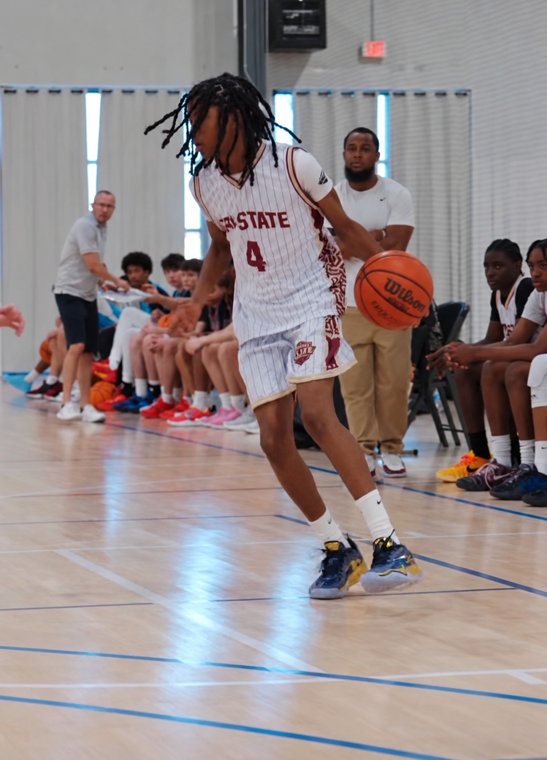 KJ Townsend dribbling in a white Tri-State uniform with his father Joe coaching behind him